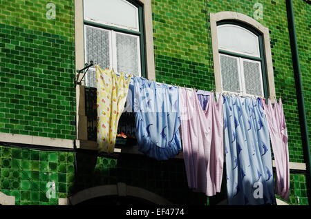 Servizio lavanderia appeso al di fuori di una vecchia casa di Lisbona con una sorprendente verde piastrelle in ceramica sulle pareti. Foto Stock