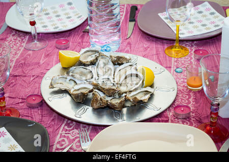 Ostriche e spicchi di limone su un set table. Foto Stock