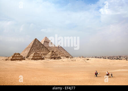 Piramidi di Giza con il cammello e turisti a piedi passato Foto Stock