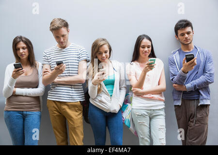 Gli studenti che usano il loro smartphone in una riga Foto Stock