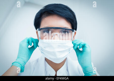 Dentista indossando maschera chirurgica e occhiali di sicurezza Foto Stock