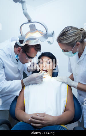 Dentista con assistente esaminando womans denti Foto Stock