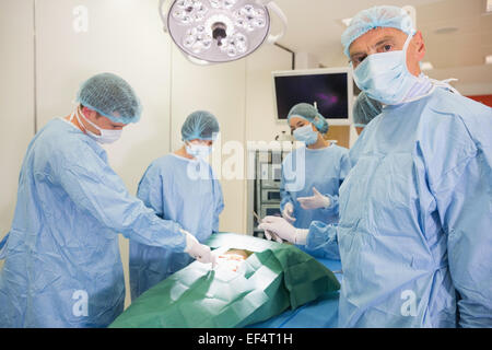 Studente di medicina guardando la fotocamera durante la pratica della chirurgia Foto Stock