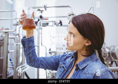 Elegante bruna nella camicia di denim guardando il bicchiere di birra Foto Stock