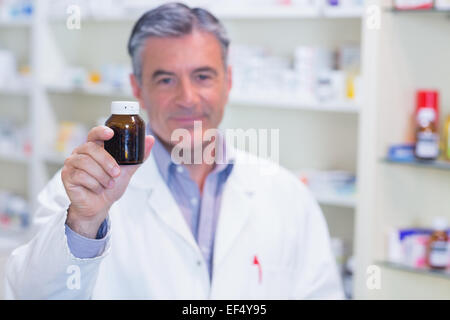 Il farmacista che mostra un flacone di farmaco alla fotocamera Foto Stock