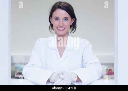 Biologo femmina sorridente verso la telecamera fuori dalla finestra Foto Stock