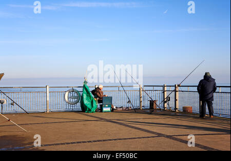 Una vista del mare i pescatori la pesca al fine di Southwold Pier, Suffolk, Inghilterra, Regno Unito. Foto Stock