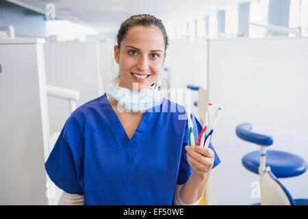 Ritratto di un sorridente dentista che mostra uno spazzolino da denti Foto Stock