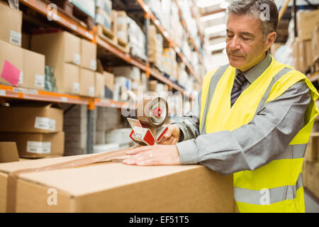 Lavoratore di magazzino la sigillatura di scatole di cartone per la spedizione Foto Stock