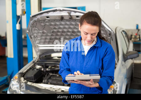 Mechanic utilizzando tablet per fissare l'auto Foto Stock