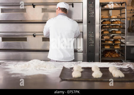 Baker apertura forno a mettere la pasta in Foto Stock