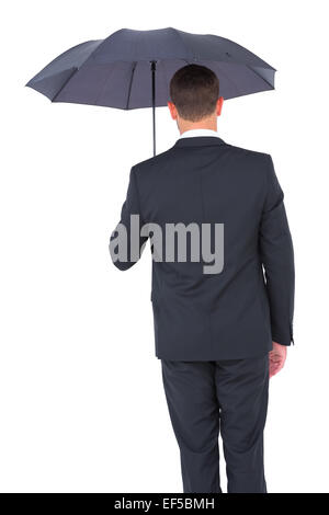 Imprenditore rifugiandosi sotto ombrellone nero Foto Stock