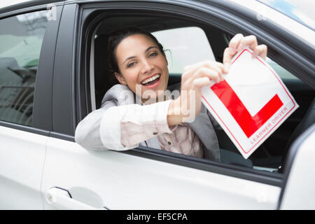 Sorridente driver femmina sistemando il suo segno L Foto Stock