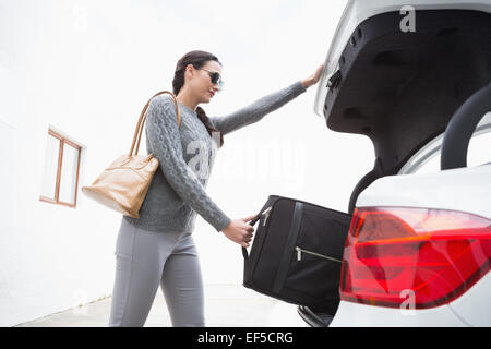 La donna tirando fuori un bagaglio del suo baule auto Foto Stock