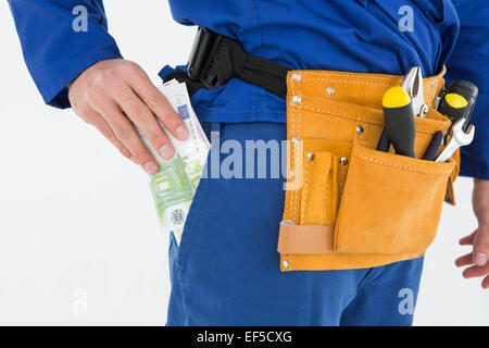 Repairman mettendo le banconote in euro in tasca Foto Stock