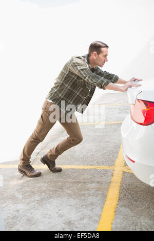 L'uomo spingendo il suo ripartiti in auto Foto Stock