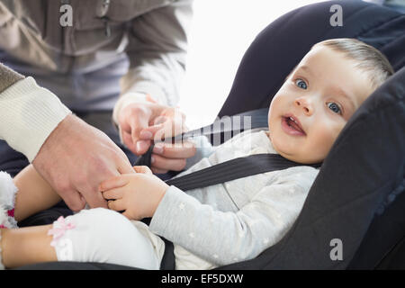 I genitori che fissano il bambino nel seggiolino per auto Foto Stock