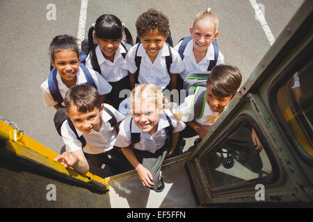 Carino scolari di salire sul bus di scuola Foto Stock