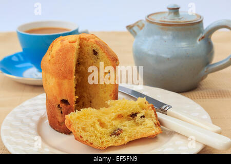 Una fetta di panettone tradizionale italiana frutto di Natale torta di pane su una piastra con una tazza di tè e teiera su un tavolo. Inghilterra, Regno Unito Foto Stock