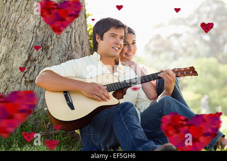 Immagine composita dell uomo a suonare la chitarra mentre guardando in lontananza con il suo amico Foto Stock