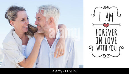 Immagine composita di attraente coppia sposata abbracciando in spiaggia Foto Stock