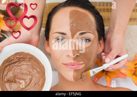 Immagine composita della pacifica brunette ottenendo un fango applicato al viso Foto Stock