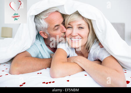 Immagine composita di primo piano di uomo maturo kissing womans guancia a letto Foto Stock