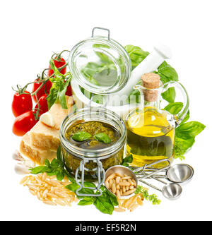 Ingredienti per il fresco verde pesto: olio d'oliva, basilico, parmigiano, pinoli, pomodoro. Cibo sano. Foto Stock