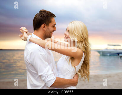Coppia felice costeggiata sulla spiaggia al tramonto sullo sfondo Foto Stock