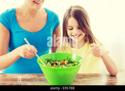 Bambina con madre insalata di miscelazione in cucina Foto Stock