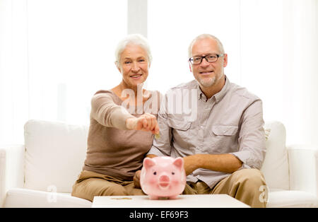 Coppia senior con il denaro e il salvadanaio a casa Foto Stock