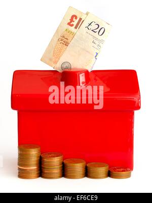 Un rosso casa denaro box con piccole pile di monete di fronte e note sulla parte superiore Foto Stock