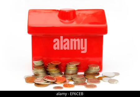 Un rosso casa denaro box con piccole pile di monete nella parte anteriore Foto Stock