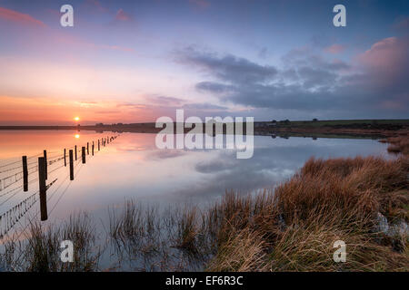 Bel tramonto su Dozmary Pool l'unico lago naturale in Bodmin Moor in Cornovaglia e immerso nella leggenda arturiana Foto Stock