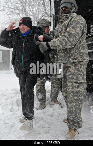 Un esercito americano soldato dell'esercito del Massachusetts National Guard assiste un residente a filamento durante la evacuazione come tempesta invernale Juno arresta il nordest degli Stati Uniti con neve pesante e alta venti Gennaio 27, 2015 in Scituate, Massachusetts. Foto Stock