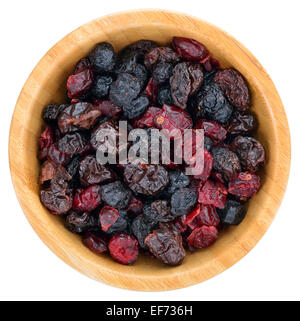 Mix essiccato bacche Frutta. Mirtilli rossi secchi, uvetta, le ciliege acide, mirtilli nella ciotola di legno isolato su sfondo bianco. A Foto Stock