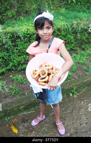 Ragazza 8 anni, con ciambelle fresche, El Castillo, Rio San Juan in Nicaragua Foto Stock