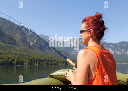 Donna in barca e pesca sul lago Foto Stock