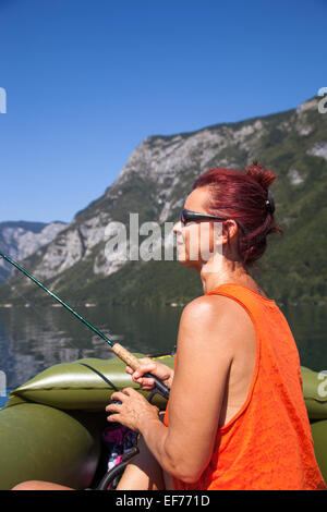 Donna in barca e pesca sul lago Foto Stock