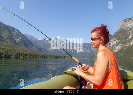 Donna in barca e pesca sul lago Foto Stock