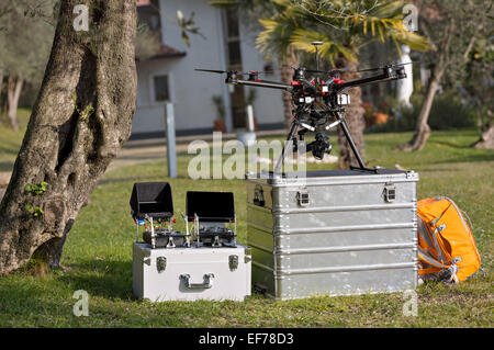 Quadcopter e drone telecomandi in appoggio su due cassette per attrezzi in alluminio contro vivido verde. Foto Stock