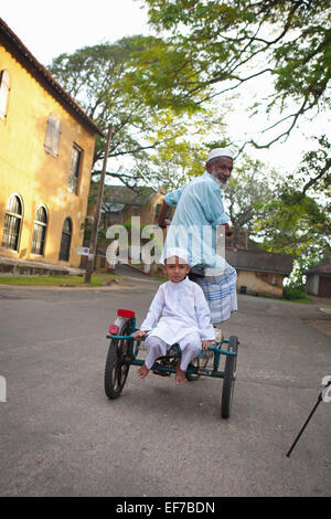 Anziani DELLO SRI LANKA uomo e bambino piccolo CICLISMO IN FORTE GALLE Foto Stock