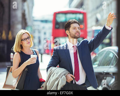 La gente di affari salutando il taxi in città Foto Stock