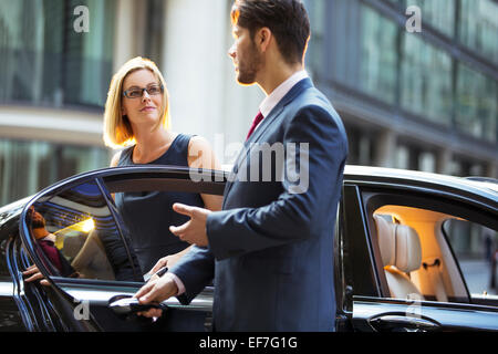 Chauffeur apertura porta auto per imprenditrice Foto Stock