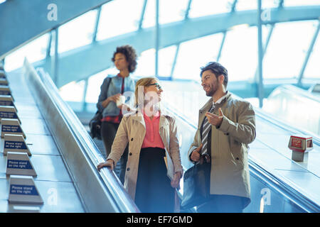 La gente di affari di parlare su escalator Foto Stock