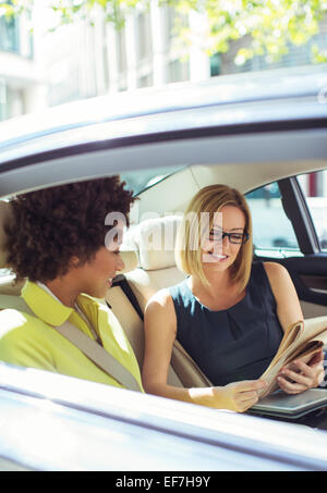 Imprenditrici leggendo il giornale in auto sedile posteriore Foto Stock