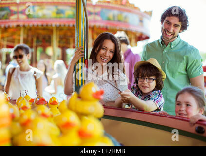 I genitori con due bambini di divertirsi con il gioco della pesca nel parco di divertimenti Foto Stock