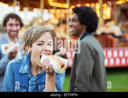 Tre giovani mangiare hot dog nel parco di divertimenti Foto Stock