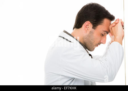 Mezza lunghezza ritratto di profilo di un premuroso medico maschio la sua testa appoggiata alle mani Foto Stock