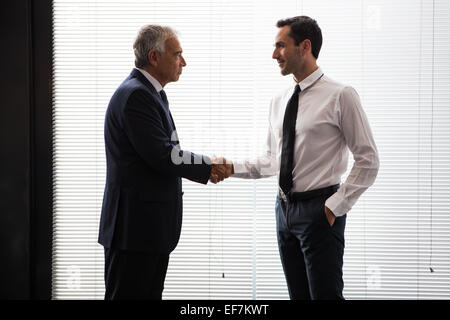Mezza lunghezza ritratto di due imprenditori in piedi e mani di scuotimento Foto Stock